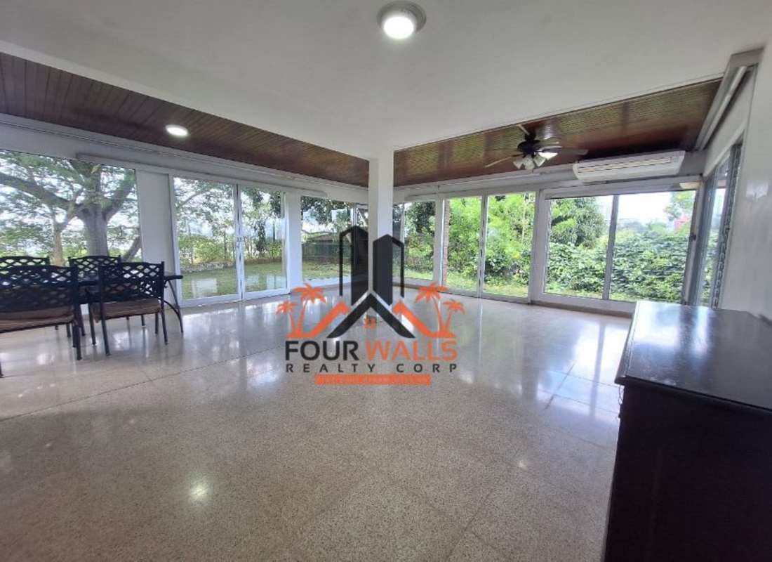 Sunroom with large glass windows, wooden ceiling, dining table, garden view in El Dorado Panama