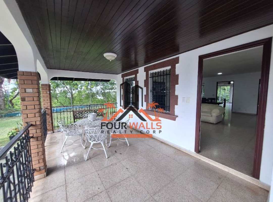 Traditional patio with wooden ceiling, metal railings, brick columns, overlooking garden in El Dorado Panama