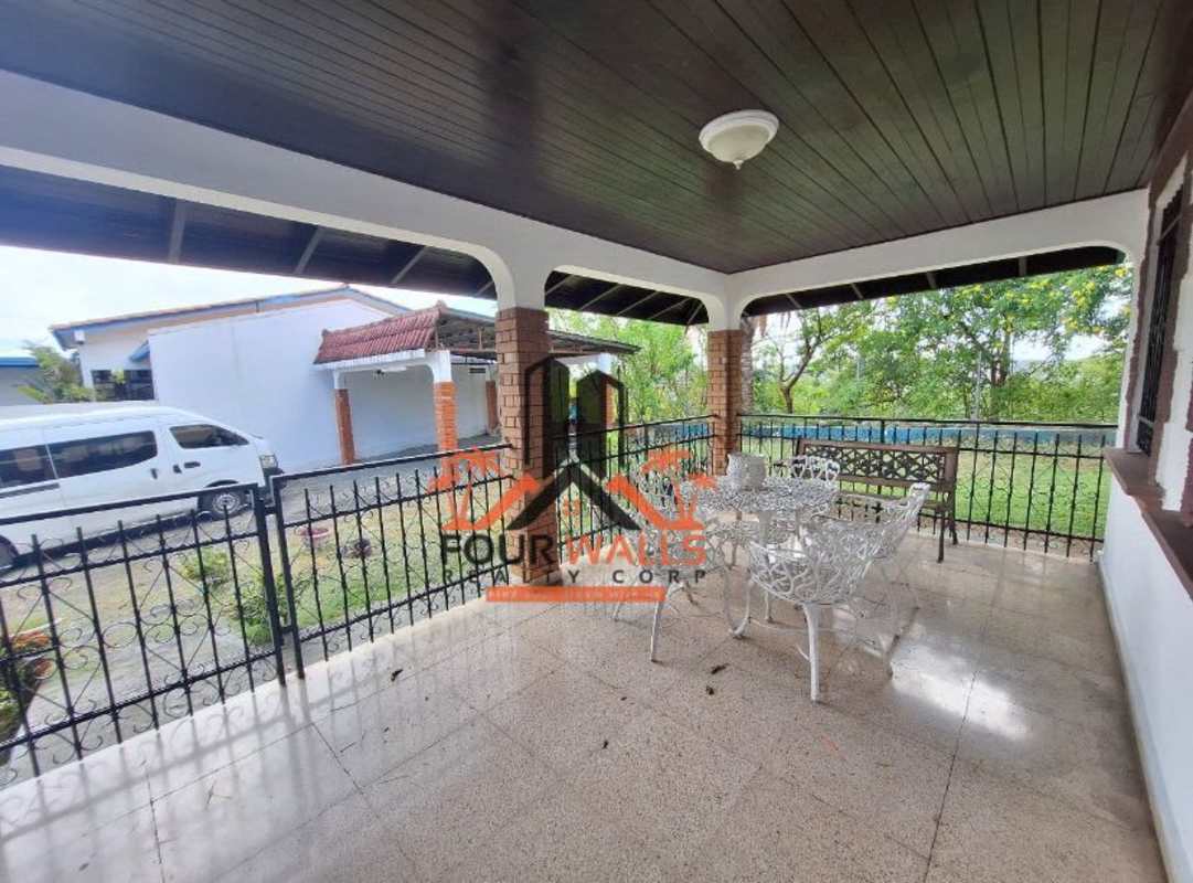Covered patio with brick columns, wood ceiling, decorative windows and garden seating in Villa de las Fuentes