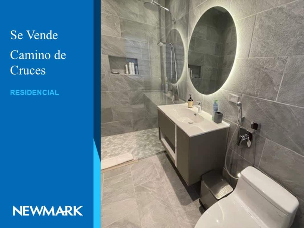 Contemporary bathroom featuring circular backlit mirror, glass shower and double sinks in El Dorado villa