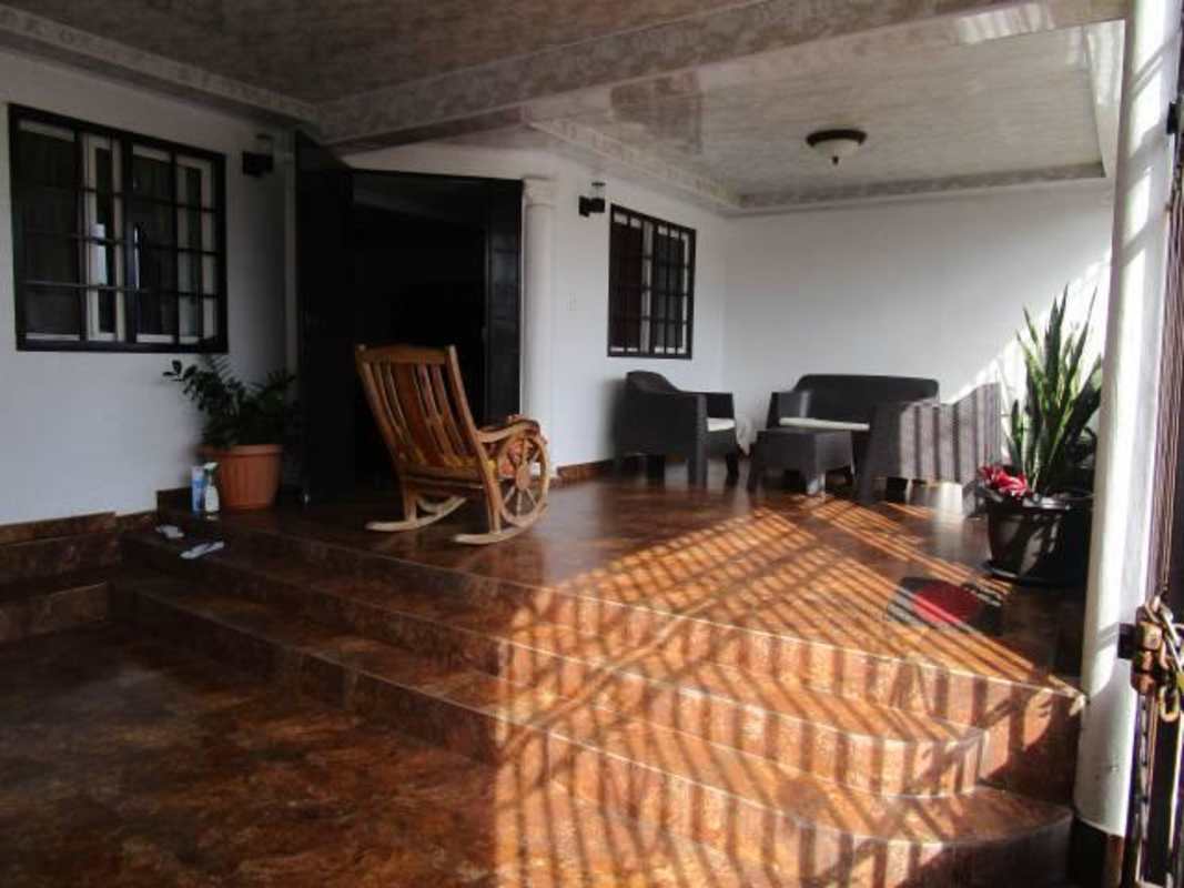 Covered porch area with outdoor seating and garden at Tocumen house Panama