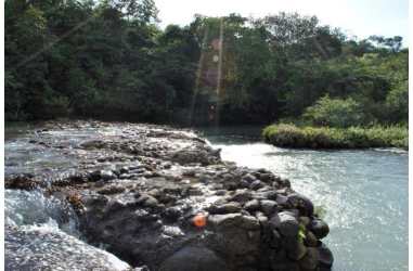 Clear water river with rocky bed and thick forest vegetation on rural farmland for sale Panama