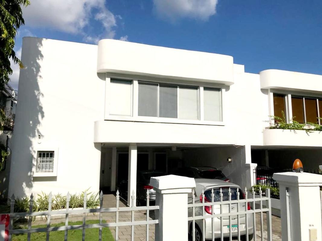 Fenced private backyard with grass lawn and tiled patio in duplex home Obarrio Panama