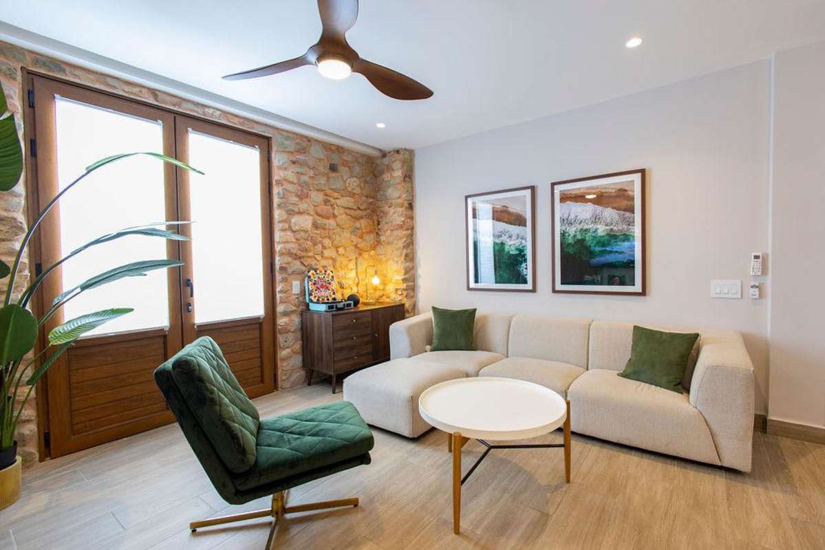 Cozy living room with exposed stone wall, sectional sofa, art accents in PH La Cuadra Casco Viejo