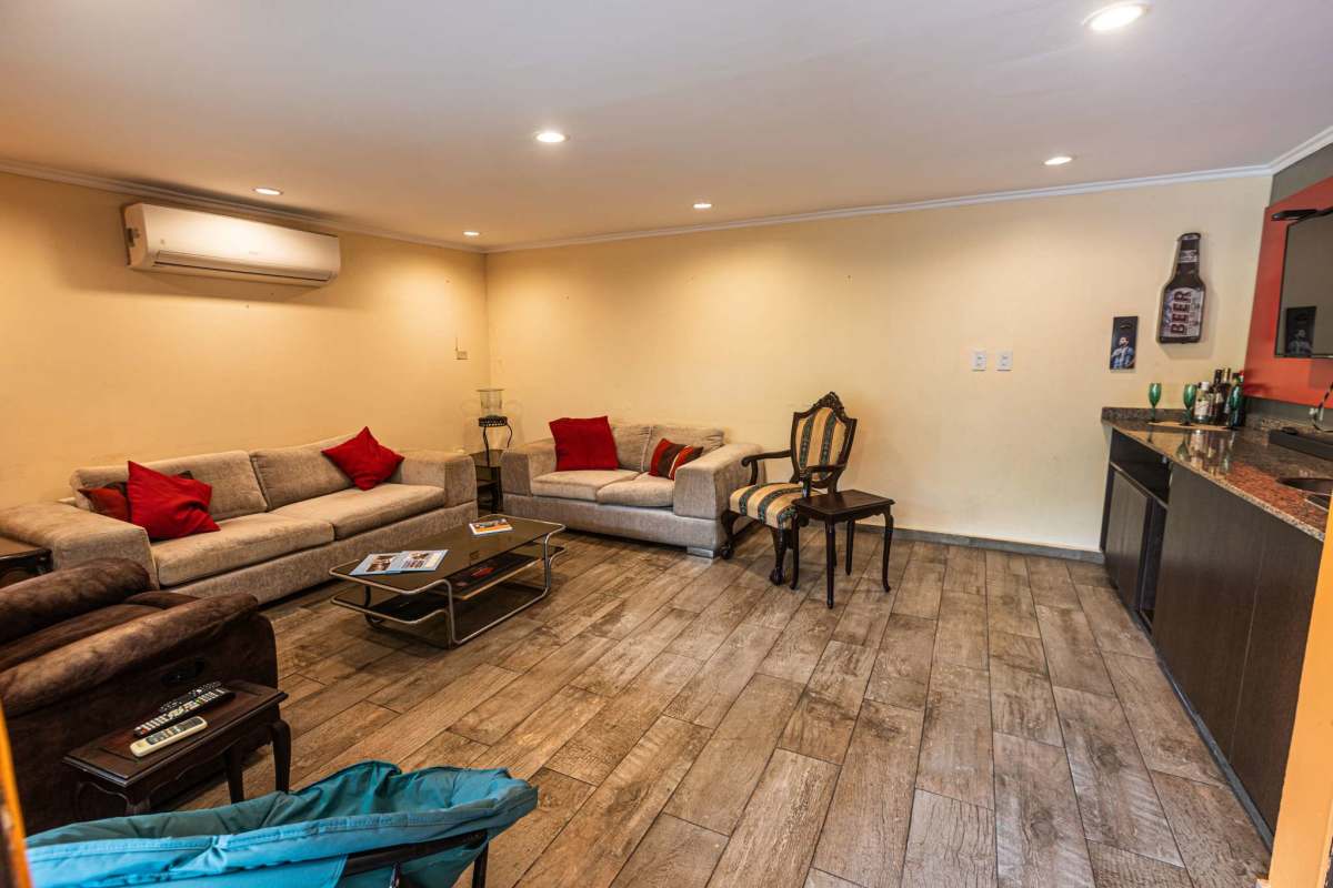 Large living room with gray sofas, bar counter and tiled flooring in El Carmen house Panama City