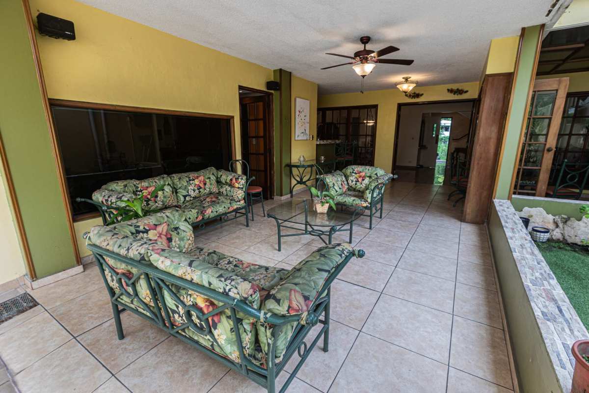 Covered patio sunroom with floral furniture and garden views at house in El Carmen Panama