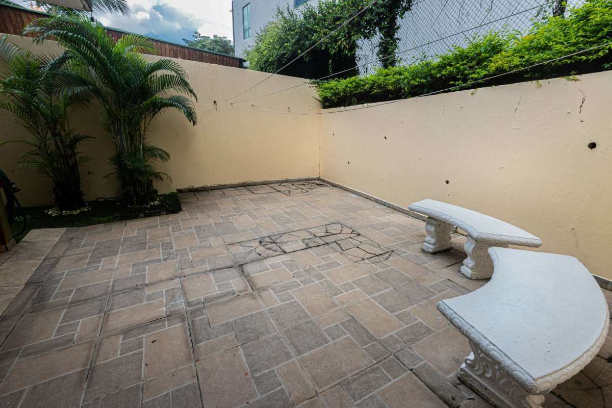 Walled courtyard patio with benches and tropical plants in El Carmen house Panama City