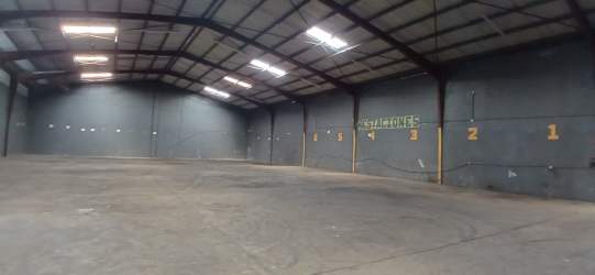 Large industrial warehouse interior with high ceiling, beams, concrete flooring located in Colon Free Zone Panama