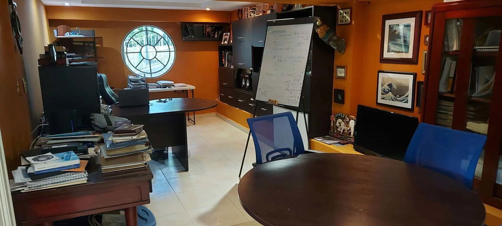 Large home office with multiple desks orange walls round window great lighting Clayton Balboa house