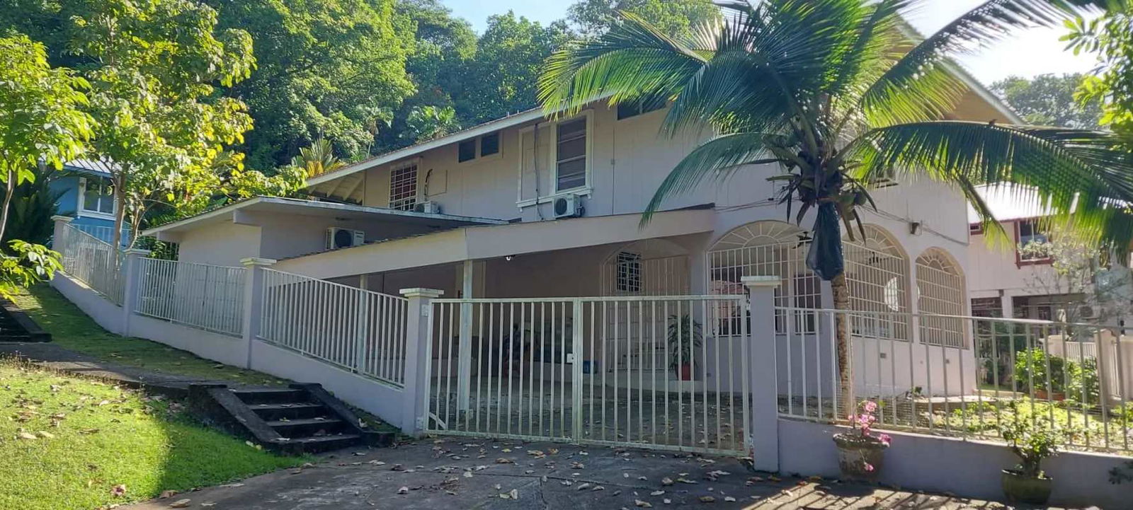 Two-story tropical-style house with gated entry garden palm trees for sale Clayton Panama