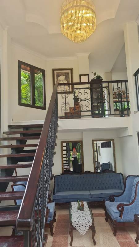 Living room with floating staircase, chandelier, and classic blue sofas in Albrook