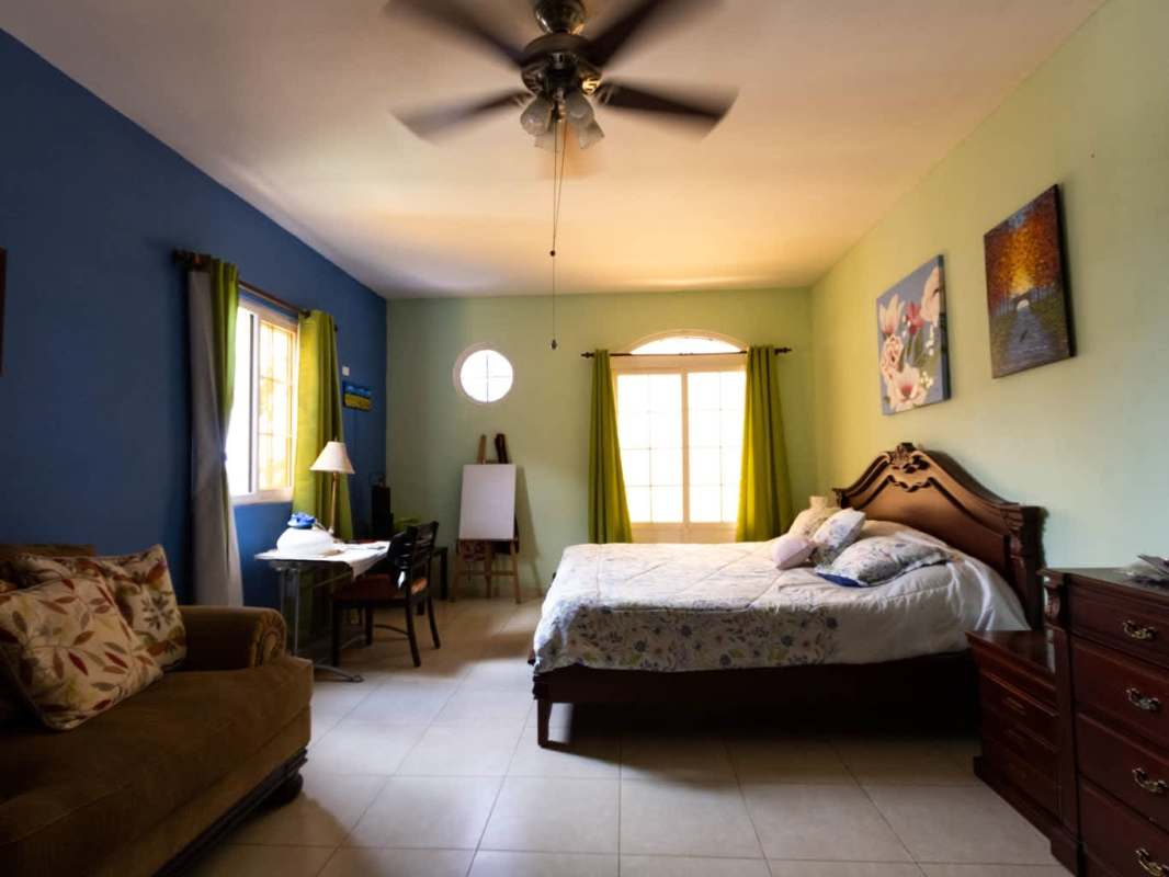 Bright living room with double-height ceiling, large arched windows, tiled floors in Centennial Ancón house