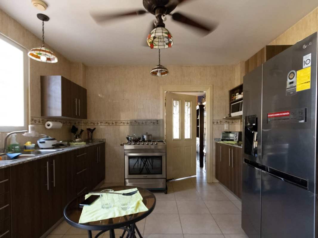 Dining room in residential house with glass-topped table, purple walls, stone window trim Centennial Panama
