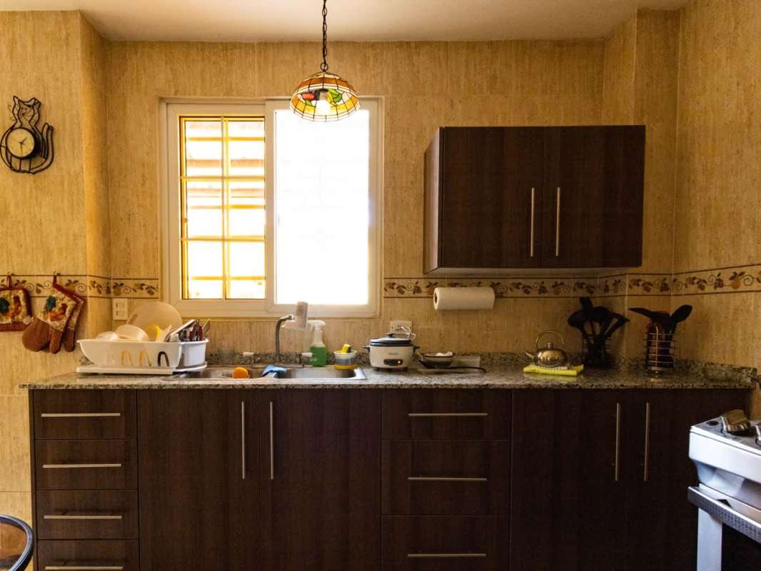 Kitchen with granite counters, wooden cabinets, ceramic tiles, pendant lights in Ancón house