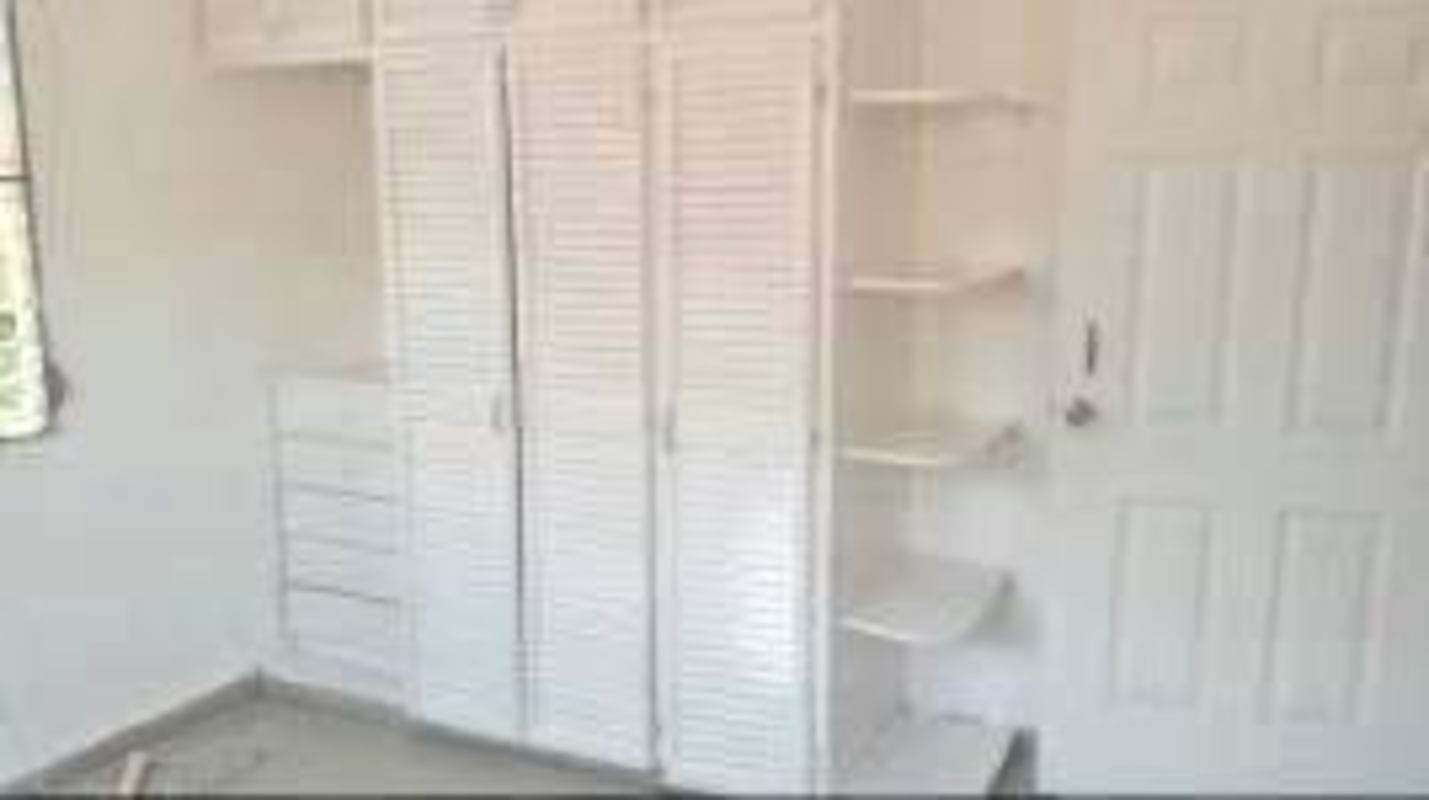 Walk-in closet with built-in wooden shelving and hanging rods in Villa Lucre house Panama