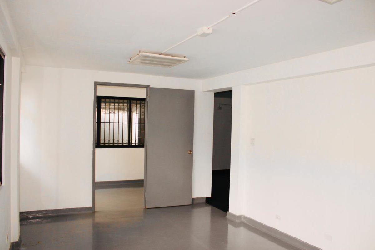 Empty room with gray flooring barred window ceiling light in duplex commercial space Obarrio Panama