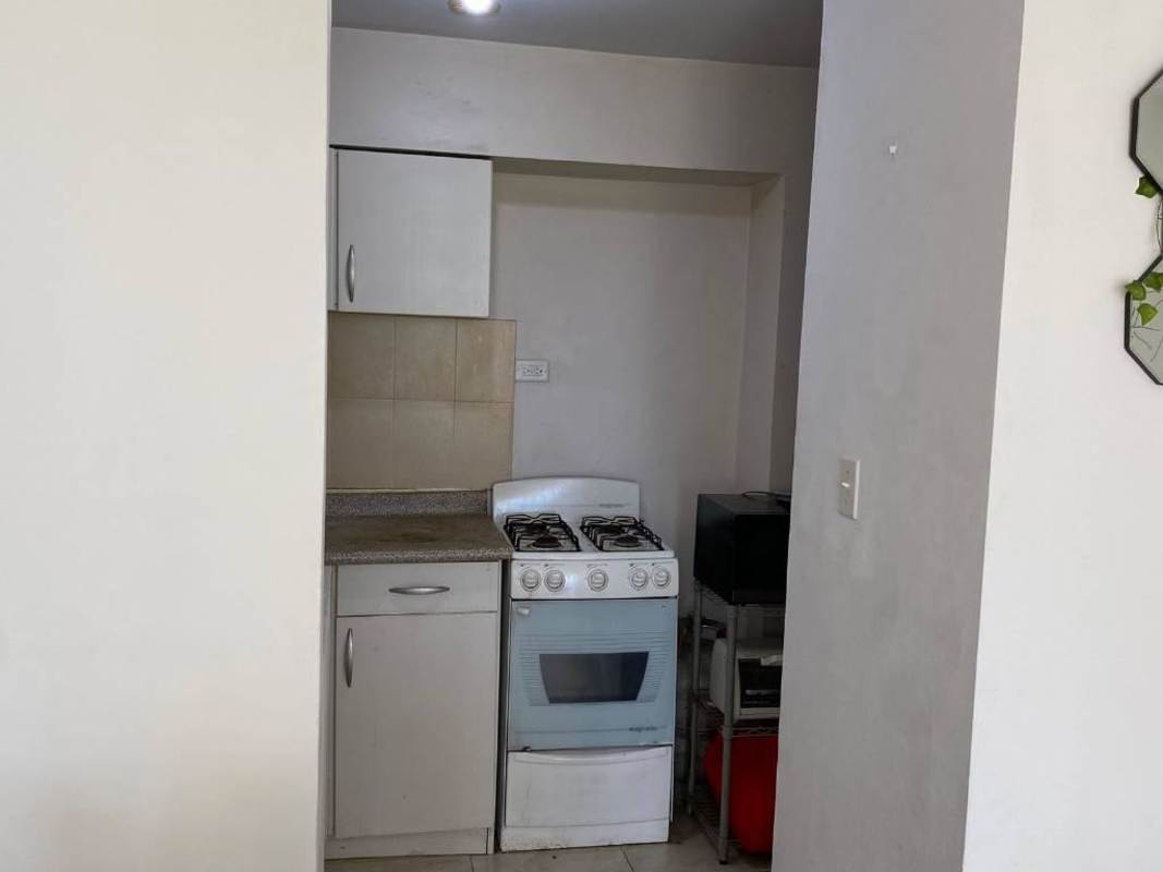 Compact kitchen with ceramic backsplash, gas stove, microwave shelf in PH Mystic Blue Panama