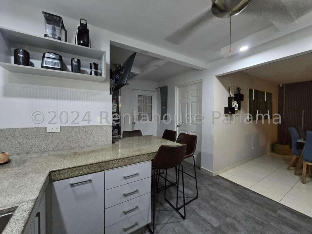 Modern kitchen with granite counters, island bar and dining area at Villa Lucre Panama house