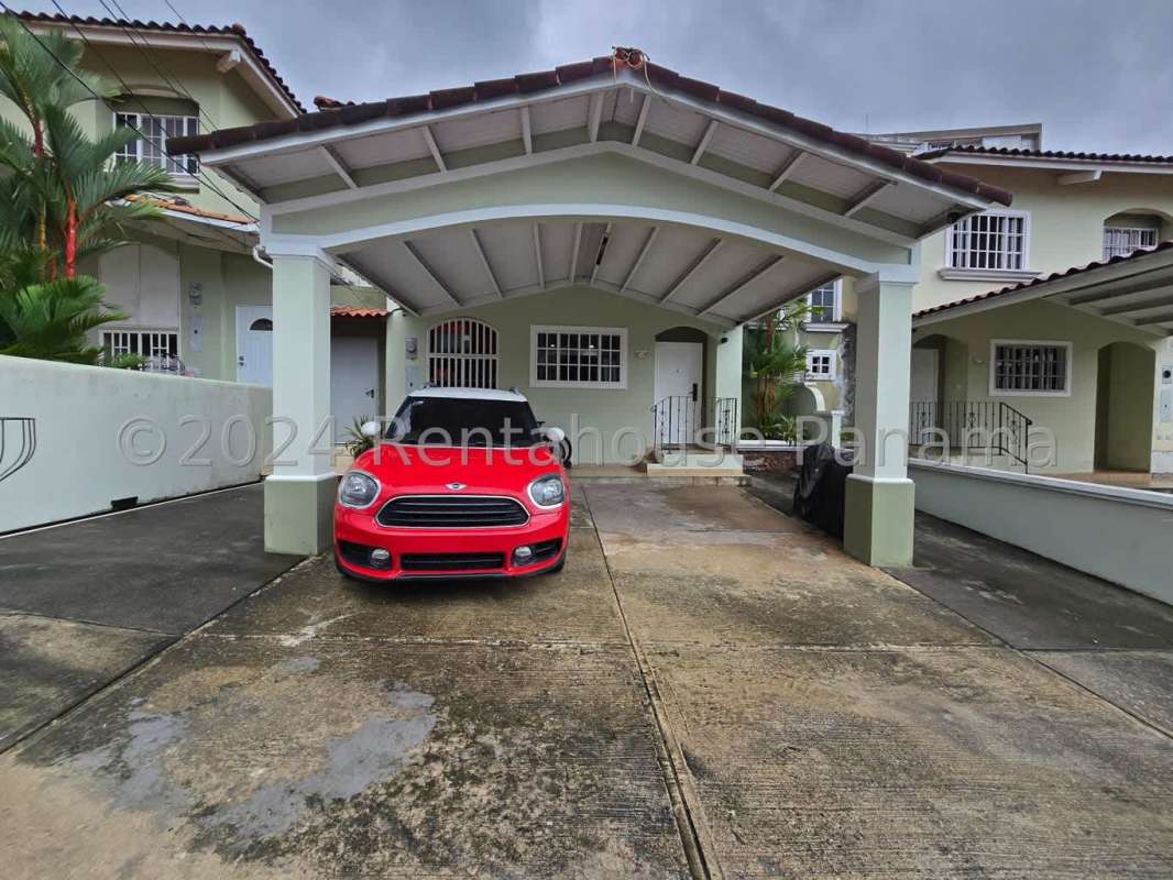 Front view of Mediterranean villa with carport, terracotta roof tiles, palm plants at Villa Lucre Panama