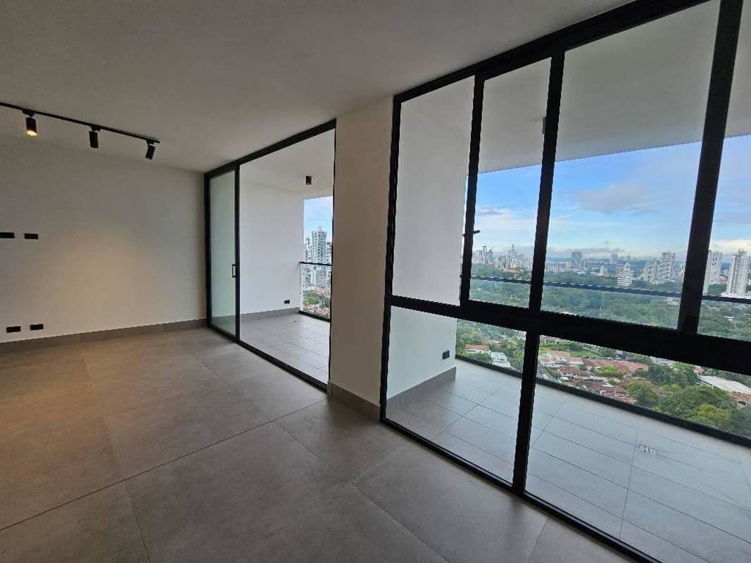 Spacious bright living room with floor-to-ceiling sliding doors and balcony with skyline view at Victory Wellness Panama