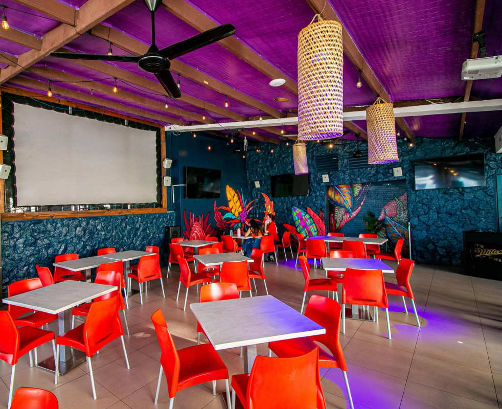 Vibrant dining room with murals, purple ceiling, TVs in commercial restaurant bar in Panama