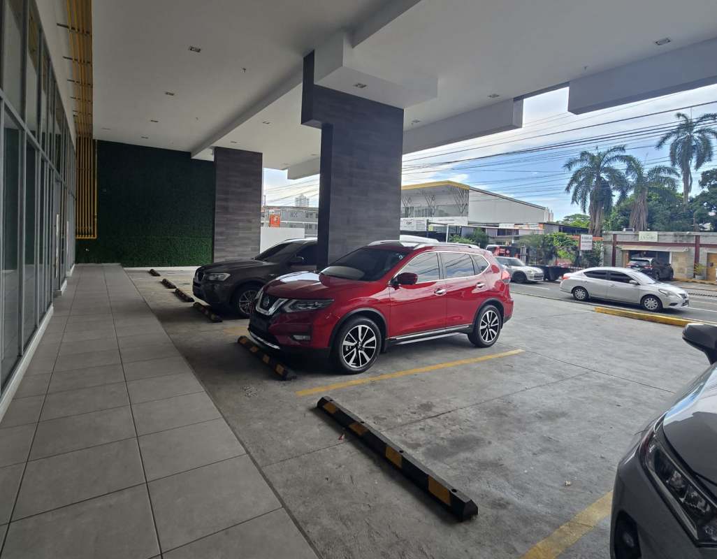 Covered parking spaces and modern commercial building facade at PH Mercado Natural on 12 de Octubre Panama City