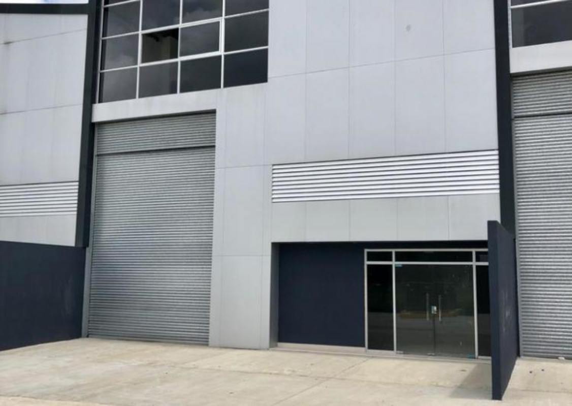 Warehouse complex entrance with metal doors and wide driveway in Transistmica Panama