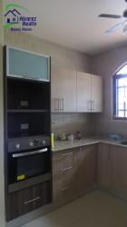 Kitchen with chimney hood, granite countertop, gas stove, beige and brown cabinetry in Volcán Panama