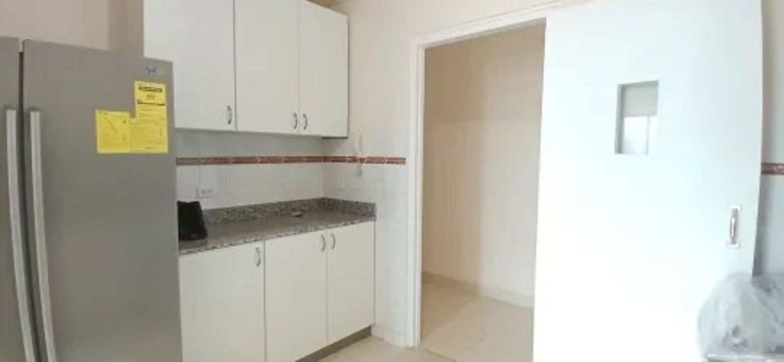 Kitchen with granite countertops, white cabinetry, refrigerator and bright lighting at PH Plaza Camino Real Betania