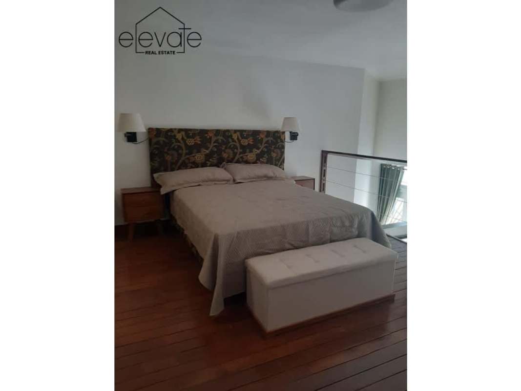 Loft bedroom with floral headboard, wooden floors, glass railing, Casco Viejo rental Panama