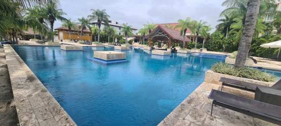 Large tropical pool with palm trees and cabanas at Buenaventura Beach Club Panama