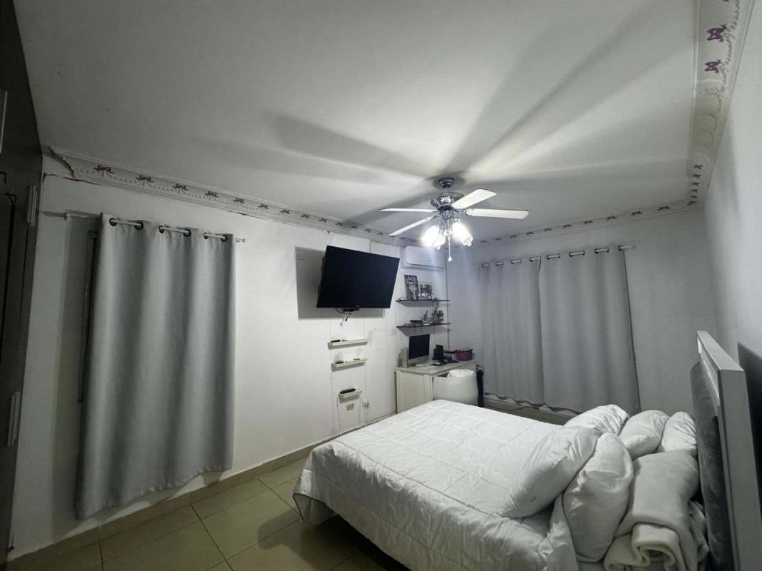 Enclosed balcony with wicker dining set, ceiling fan, panoramic windows overlooking Panama City