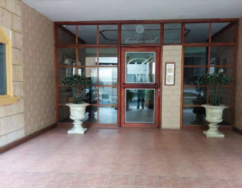 Covered building entrance with glass doors and planters PH Continental