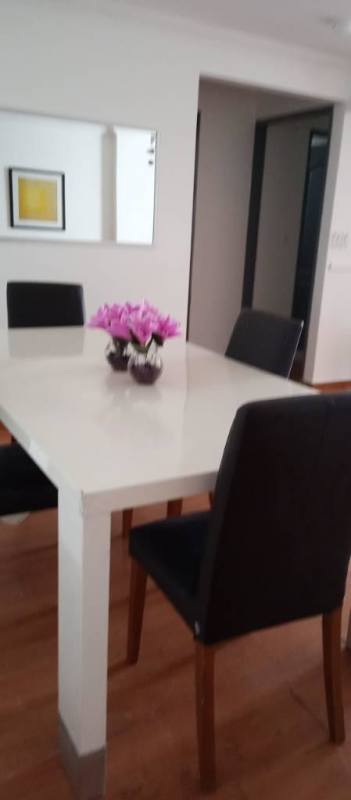 Bright minimalist dining space with white table and black chairs, large wall mirror PH Vista Hermosa Panama City