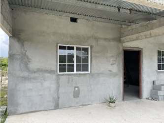 View of unfinished rural house and large fenced lot for sale in Coclé Panama