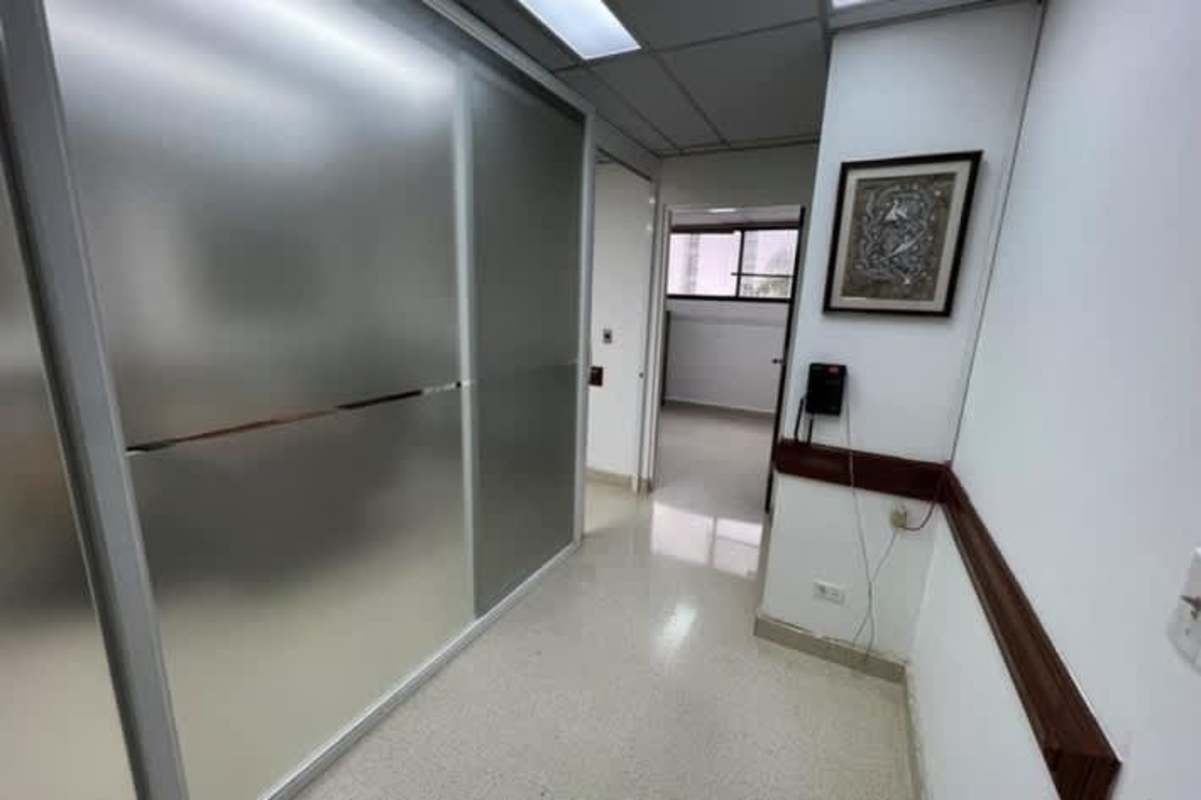 Bright corridor with frosted glass panel and artwork inside Consultorios Médicos Paitilla