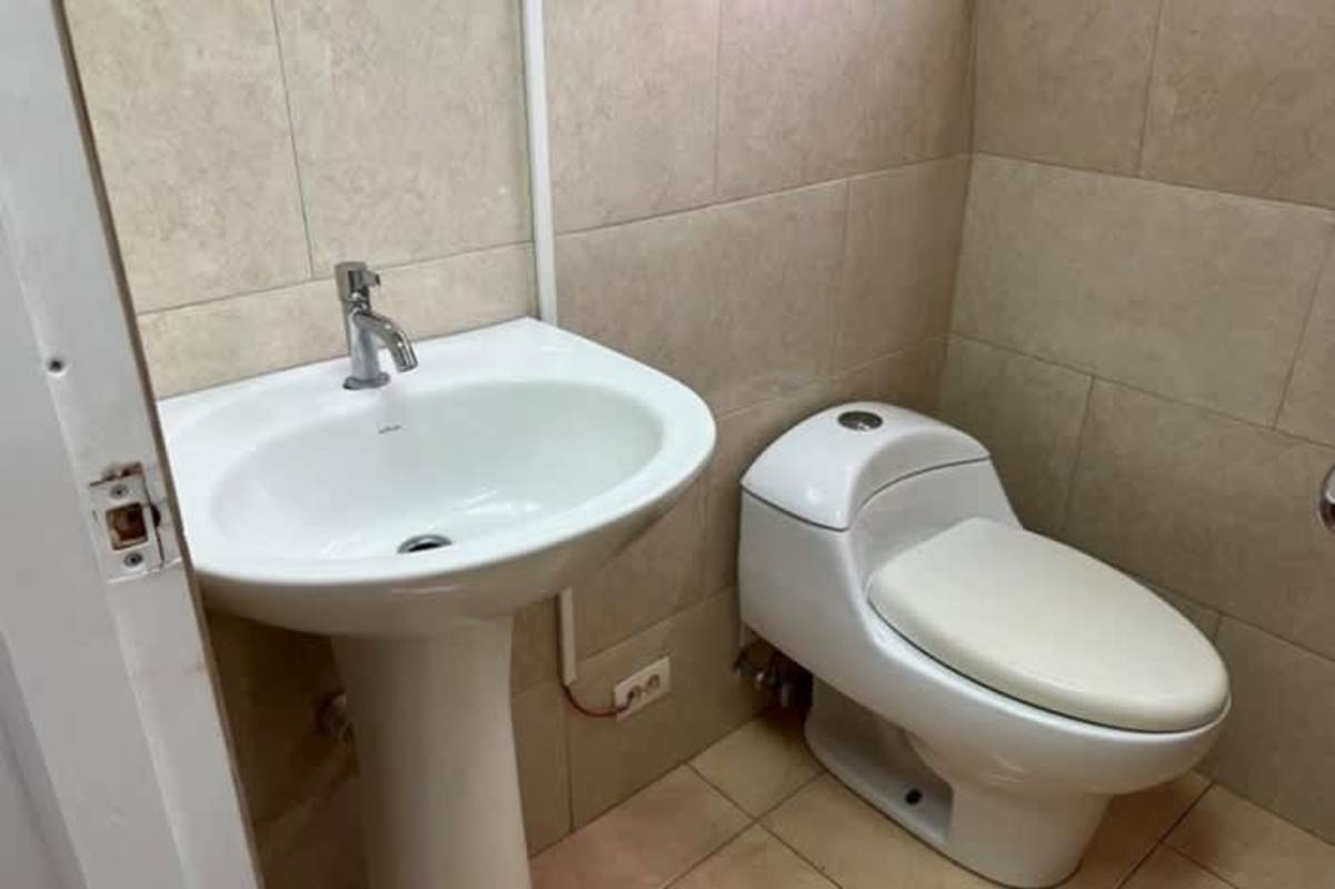 Compact modern bathroom with pedestal sink and toilet inside Paitilla medical office