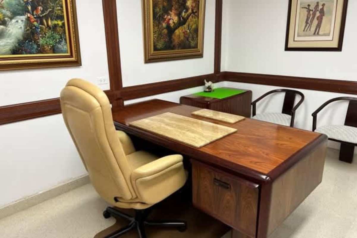 Traditional medical office with wooden desk, beige chair, and framed art for rent in Paitilla