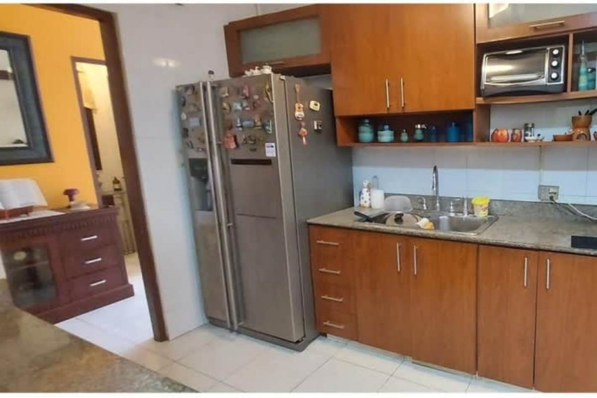 Kitchen with granite counters, wood cabinets, stainless fridge in spacious house for sale Las Cumbres Panama