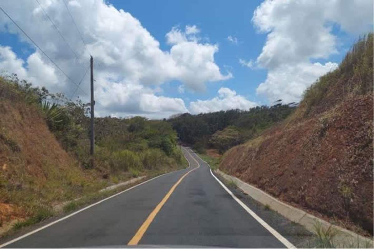 Rural mountain road with vegetation and blue sky passing forested land for sale in Panama