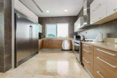 Spacious kitchen with wood cabinetry, granite counters and stainless appliances in Punta Barco penthouse Panama
