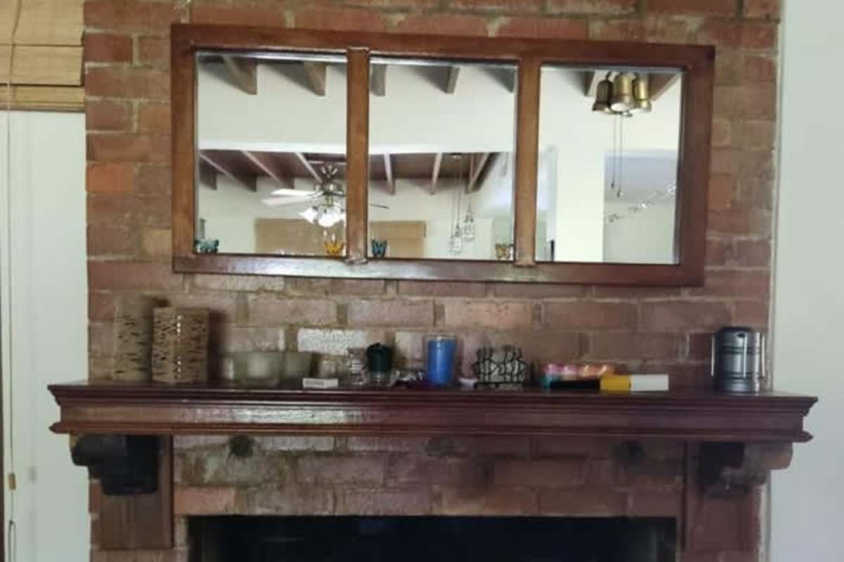 Exposed brick fireplace with wood mantel in rustic mountain house in Panama