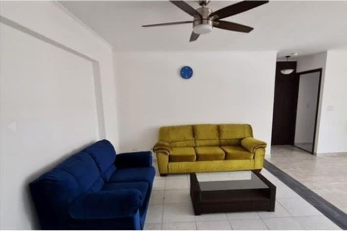 Minimalist open living and dining room with blue and yellow sofas, tiled floor at PH San Francisco Bay Panama
