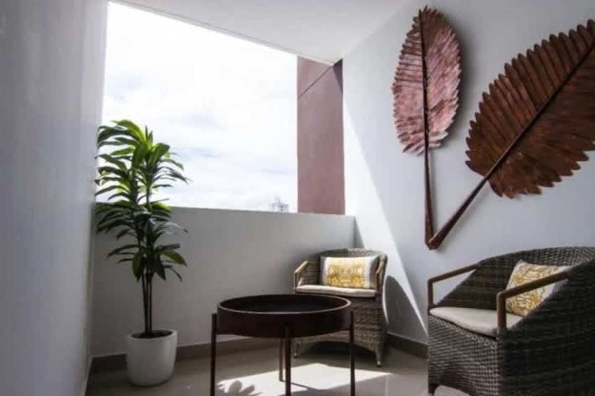 Balcony space with wicker chairs, wall art, potted plant, and partial city view in PH Taurus Tower Panama