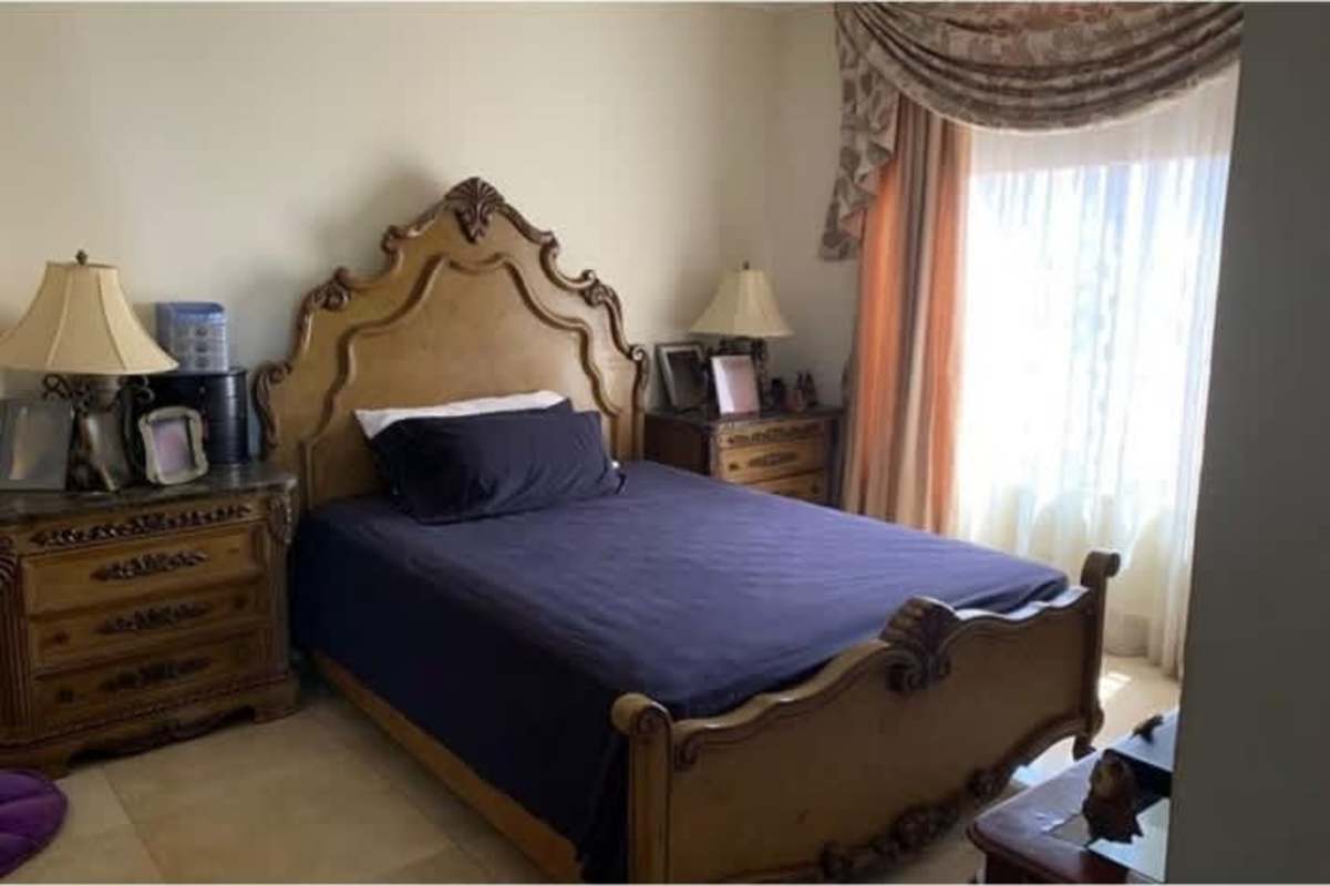 Traditional bedroom with ornate wood furniture and large draped window in Chanis house Panama City