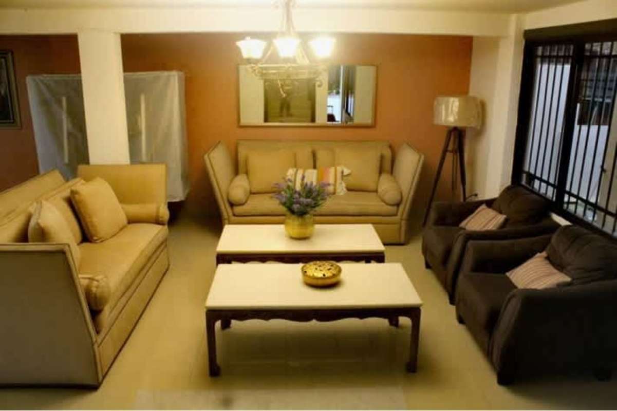 Traditional living room with beige sofas, armchairs, mirror and window in Betania Panama house