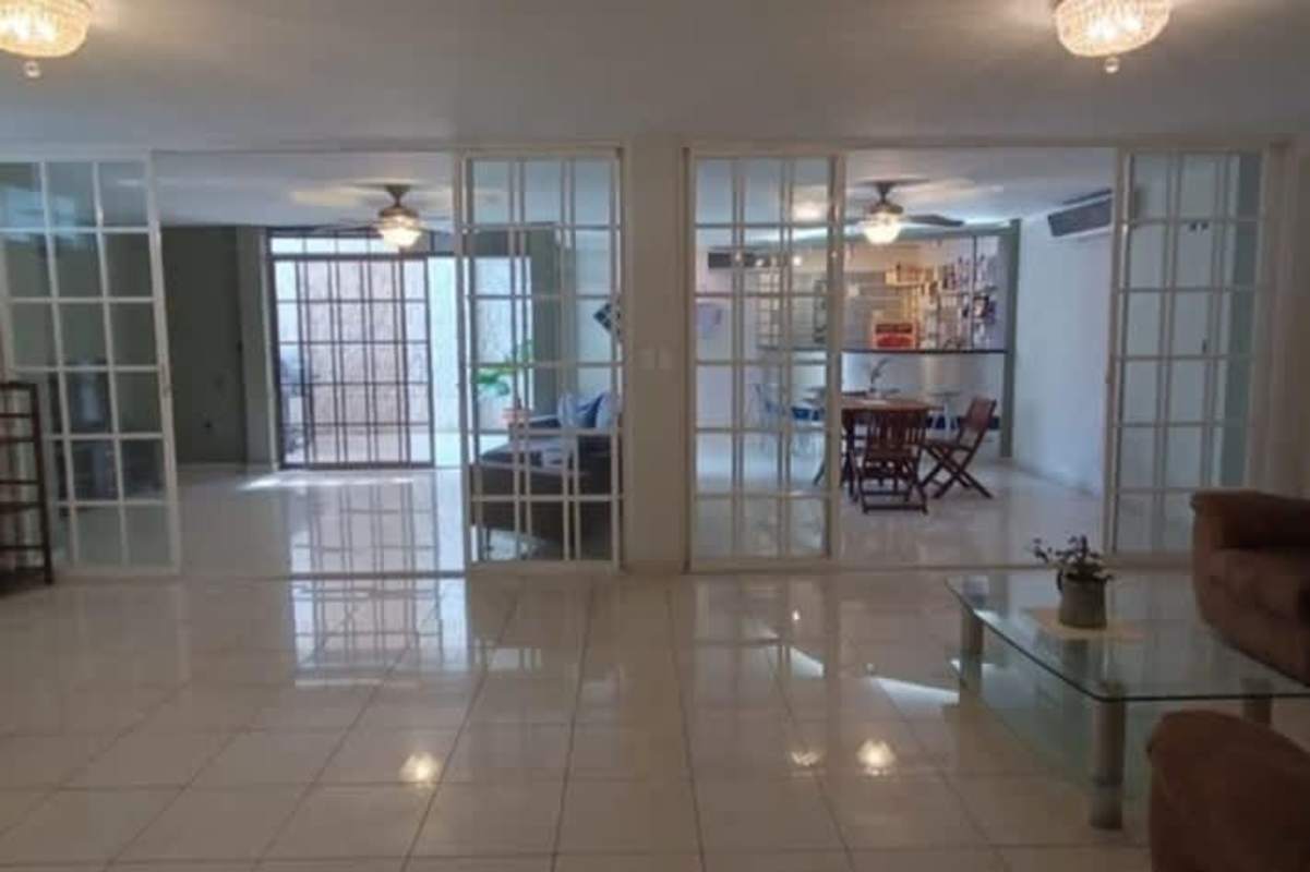 Open-plan living and dining areas with glass sliding doors in corner house El Cangrejo Panama