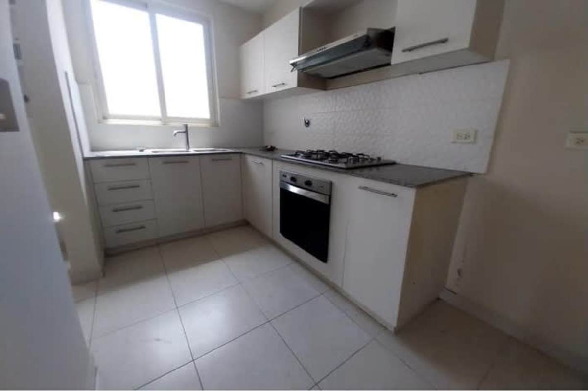 Bright L-shaped kitchen with window, stove area, and storage inside PH Versalles apartment