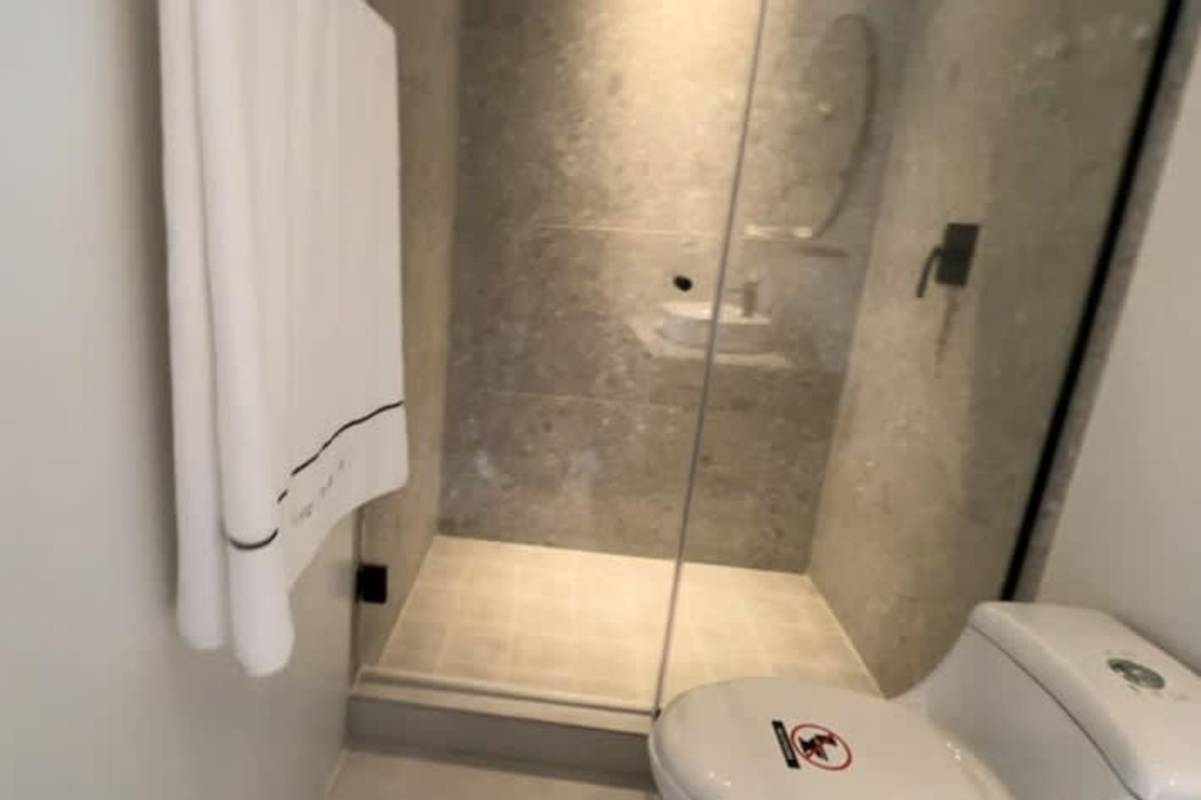 Minimalist bathroom with glass shower, stone tile, and modern fixtures at PH Arcadia Costa del Este Panama