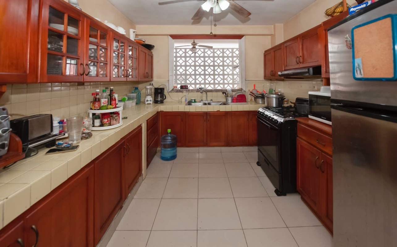 Spacious kitchen with wood cabinetry, gas stove, fridge at PH Majurova El Cangrejo Panama